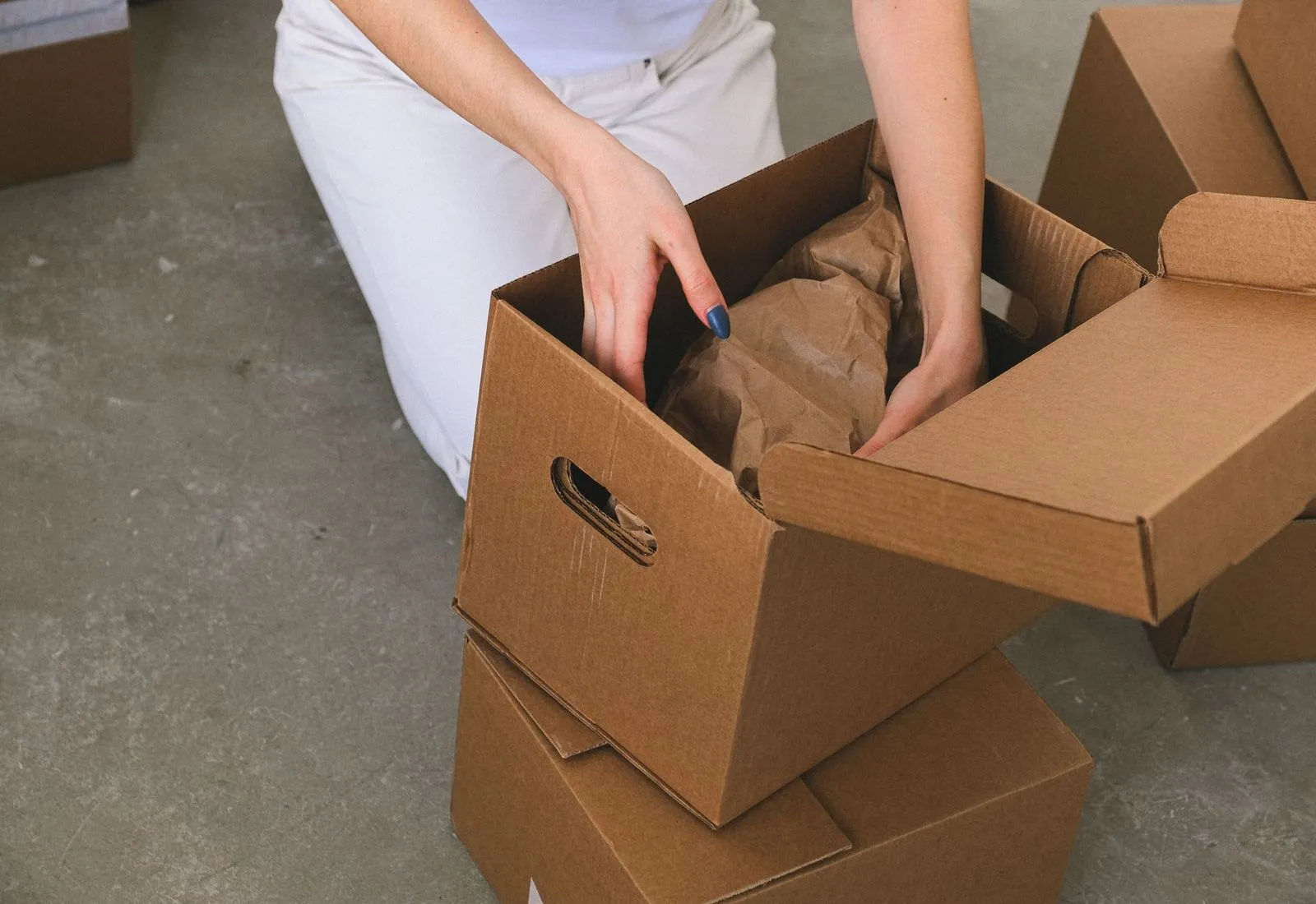 Hands packing an order into a cardboard shipping box